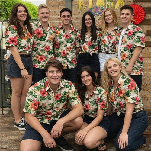 Group of nine young adults posing together, wearing matching floral Hawaiian shirts at a backyard party