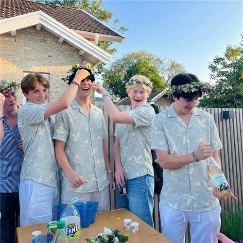 Group of young men wearing matching light blue Hawaiian shirts at a party